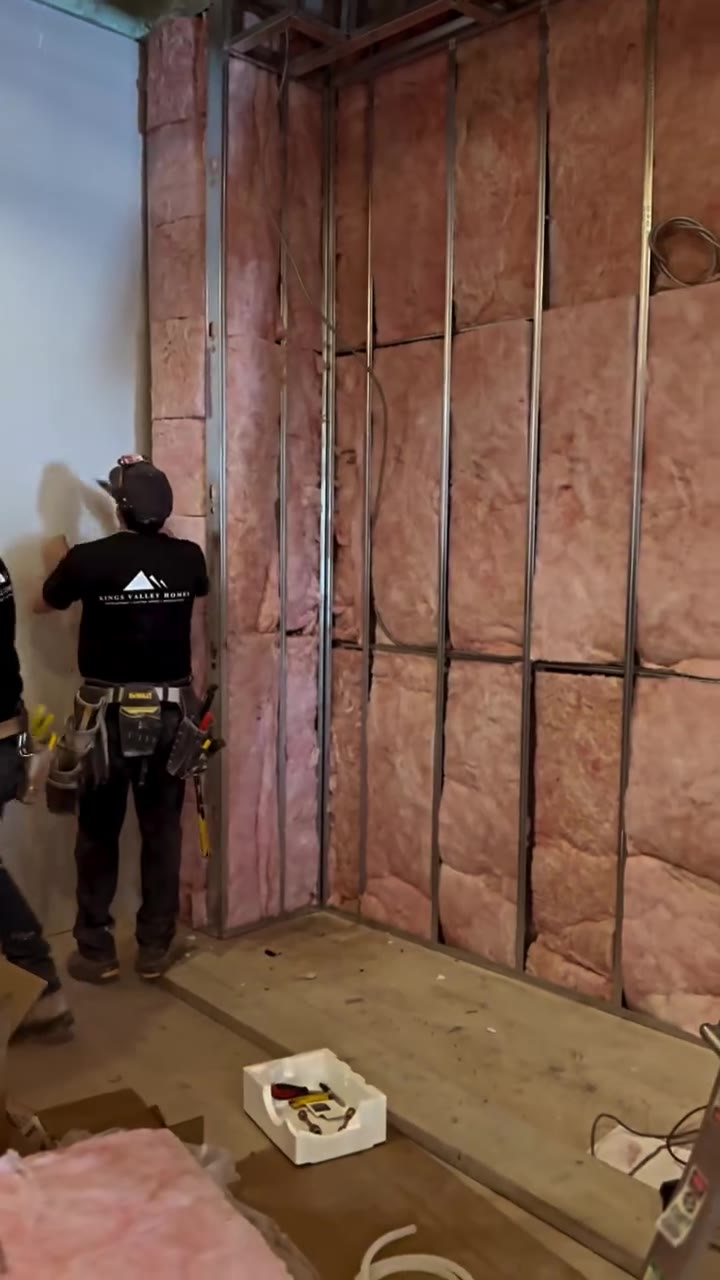 Worker installing insulation between wall studs