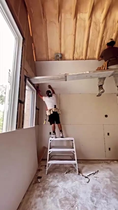 Installer on a ladder beneath exposed ceiling joists