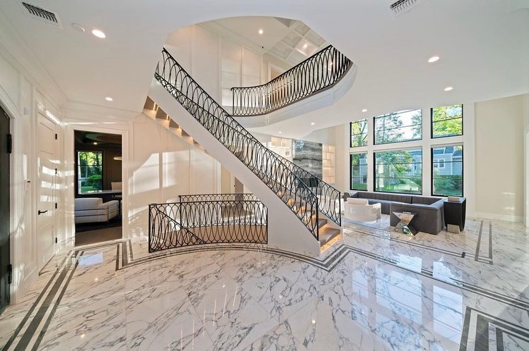 Grand foyer with a sweeping staircase, ornate metal railings, and marble flooring
