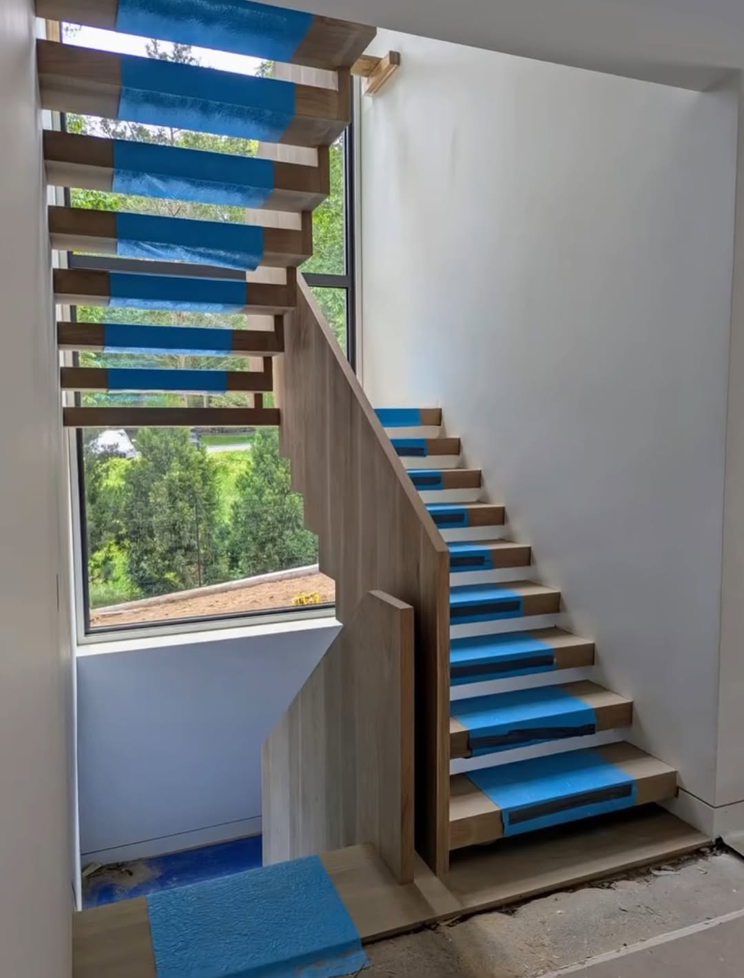Wood staircase under construction with protective tape on the treads